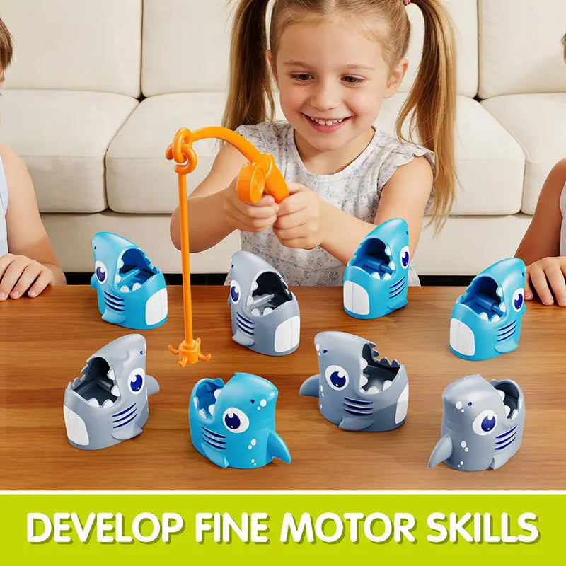 An orange fishing rod and eight blue and gray shark-shaped toys are displayed on a wooden table for children's fine motor ski