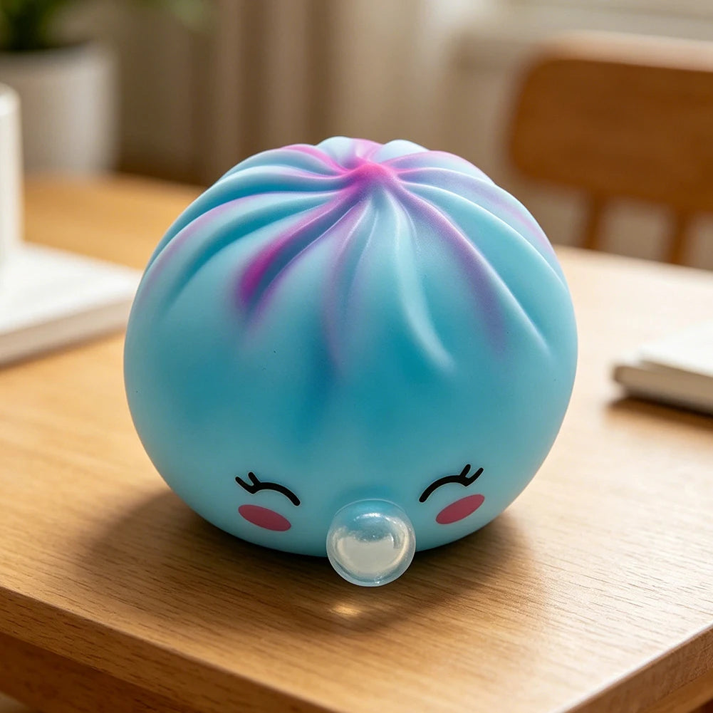 A light blue squishy stress relief toy shaped like a dumpling with pink accents resting on a wooden surface.
