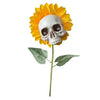 A decorative stake featuring a skull placed in the center of a bright yellow sunflower head.