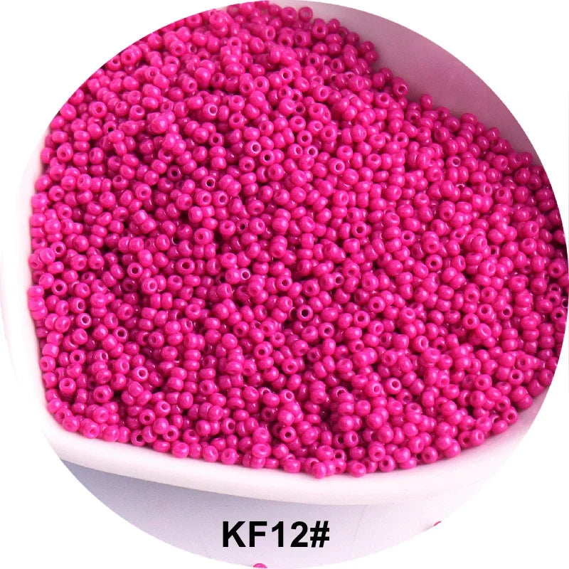 A pile of bright pink glass seed beads in a white bowl.