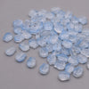 A pile of translucent light blue glass beads shaped like tulip flowers.
