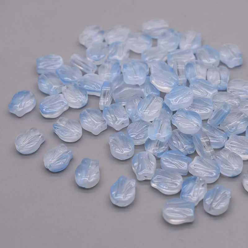 A pile of translucent light blue glass beads shaped like tulip flowers.