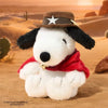 A white dog plush doll wearing a brown cowboy hat and a red bandana, set against a desert landscape.