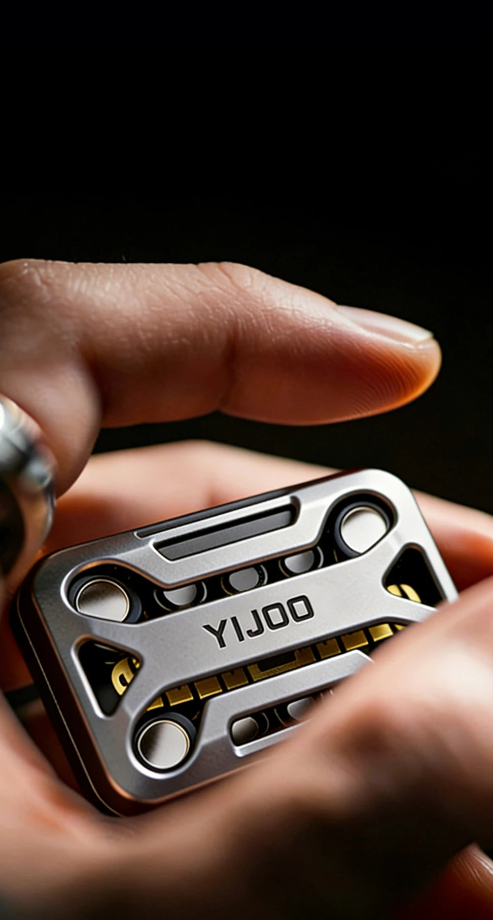 A hand holds a silver metal magnetic fidget slider with yellow accents, showing the YIJOO brand.