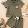 A set of olive green baby clothing featuring a short-sleeved t-shirt with a bear print and matching shorts.