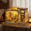 A detailed miniature dollhouse kit of a wooden jewelry store with glass display cases and LED lights.