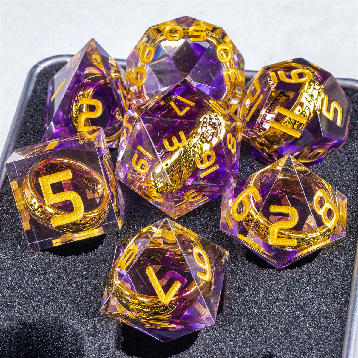 A collection of purple resin dice with golden elven numbers, set against a dark surface.