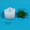A white silicone mold shaped like a cactus or succulent, next to five green silicone spheres.