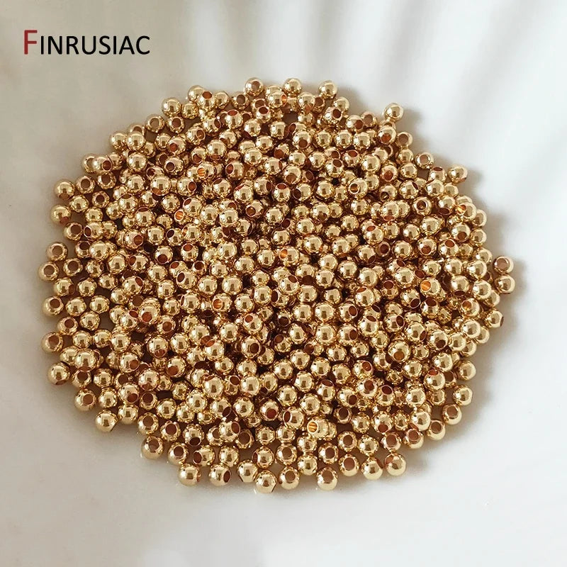 A pile of small gold-plated brass round spacer beads for jewelry making.
