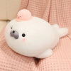 A white seal plush toy with a pink octopus hat resting on a pink textured fabric.