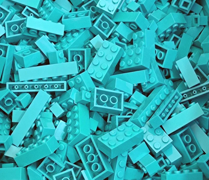A pile of light blue and teal plastic building blocks scattered on a surface.