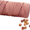 A skein of pink natural cotton macrame rope coiled and several loose balls of the same material.