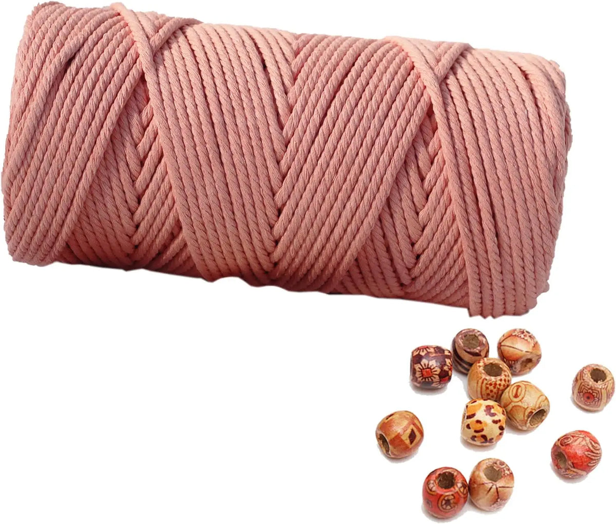 A skein of pink natural cotton macrame rope coiled and several loose balls of the same material.