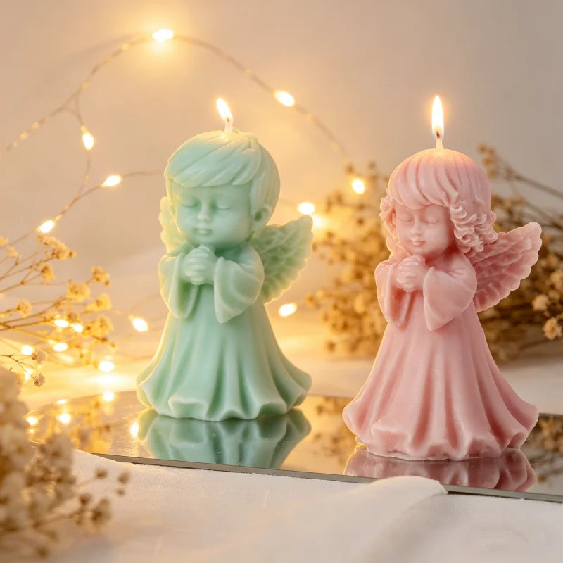 A pair of silicone molds shaped like praying angels in mint green and pink are displayed with glowing fairy lights.