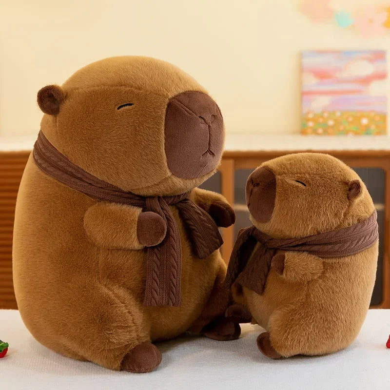 A brown plush capybara stuffed animal wearing a brown knit scarf sitting on a white surface.