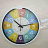 A round analog teaching clock with a colorful face and numbers, showing the time.