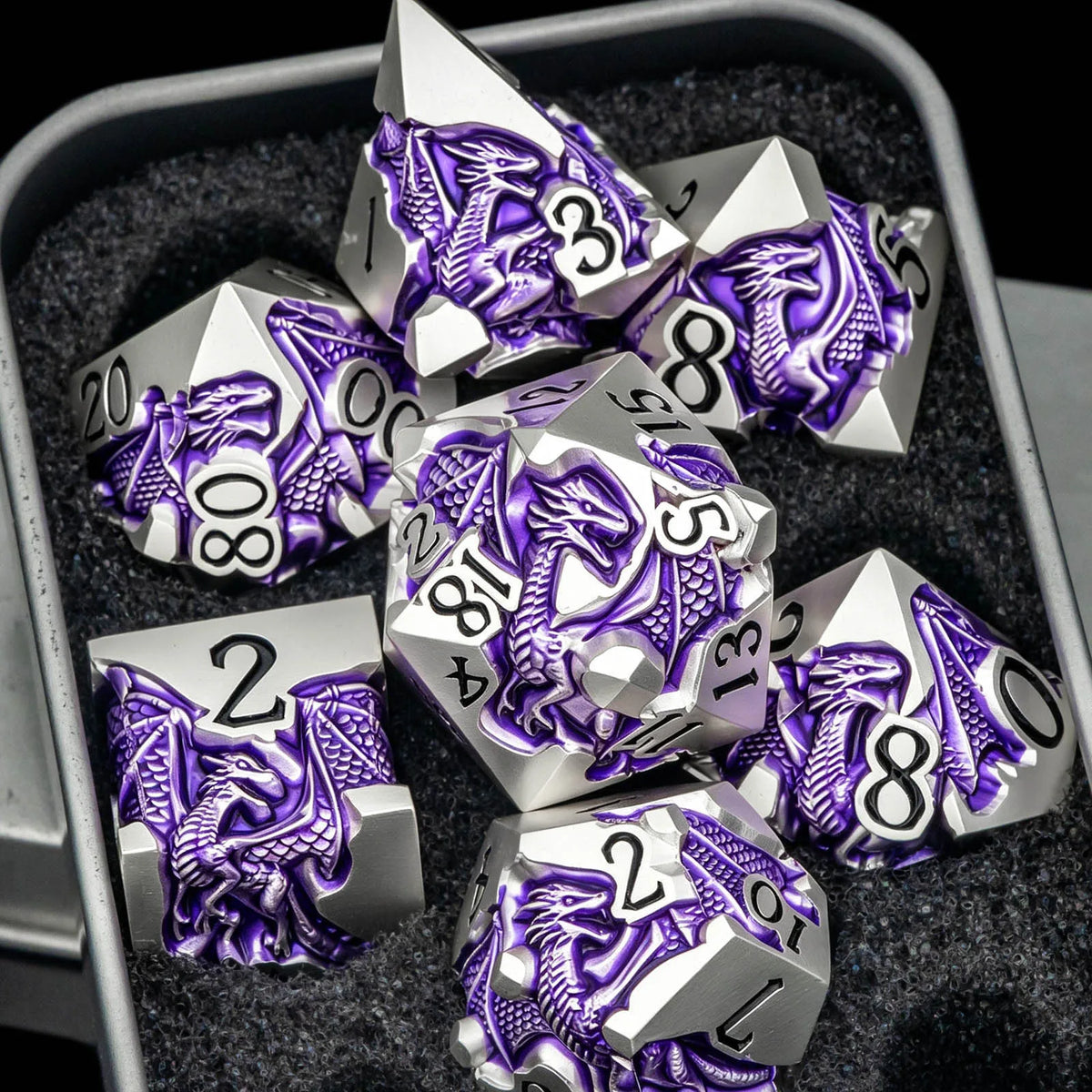 A set of silver and purple dragon-themed metal dice resting in a dark container.