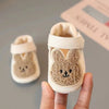 A pair of adorable bear soft sole first walker shoes for babies in cream and brown colors being held by a hand.