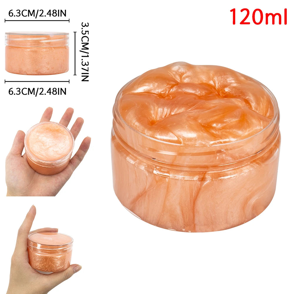 A clear glass jar of orange-tinted slime or putty with glitter, shown next to a hand and a measurement scale.