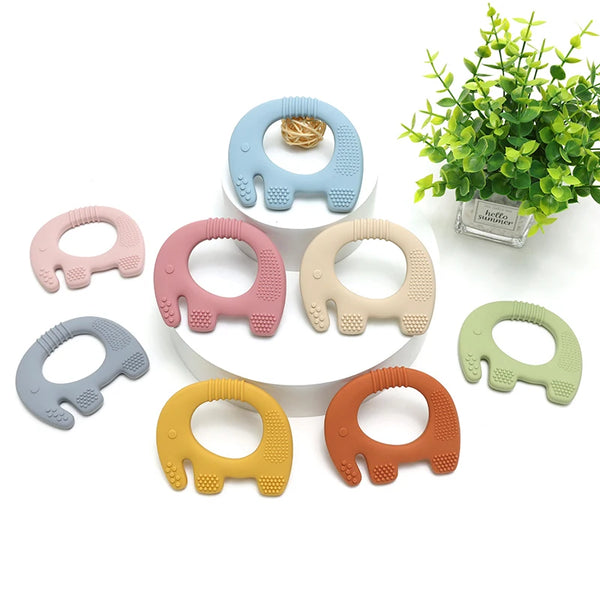 A collection of silicone elephant teethers in various pastel colors including blue, pink, beige, and yellow, displayed on a w