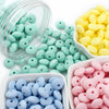 A collection of colorful silicone lentil beads in various shades of green, yellow, and pink are shown in clear containers.