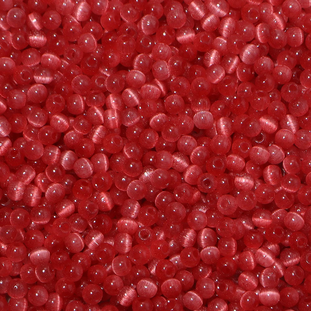 A close-up view of a colorful mix of 4mm cat eye glass beads for jewelry making.