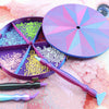 A purple rotating diamond painting storage tray organizer with various colored beads and a plastic tool is shown on a pink ba