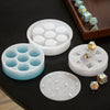A set of white silicone resin molds for creating custom dice boxes and shapes, including various hexagonal and round pieces.