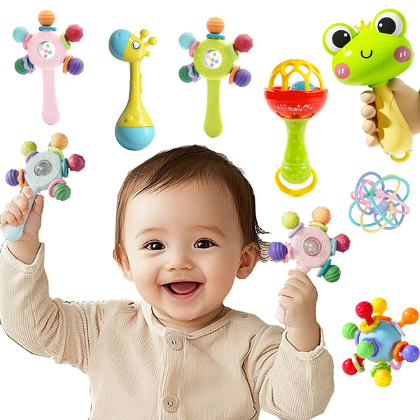 A baby is holding various silicone teether rattles and toys, including a pink rattle, yellow rattle, and green toy.