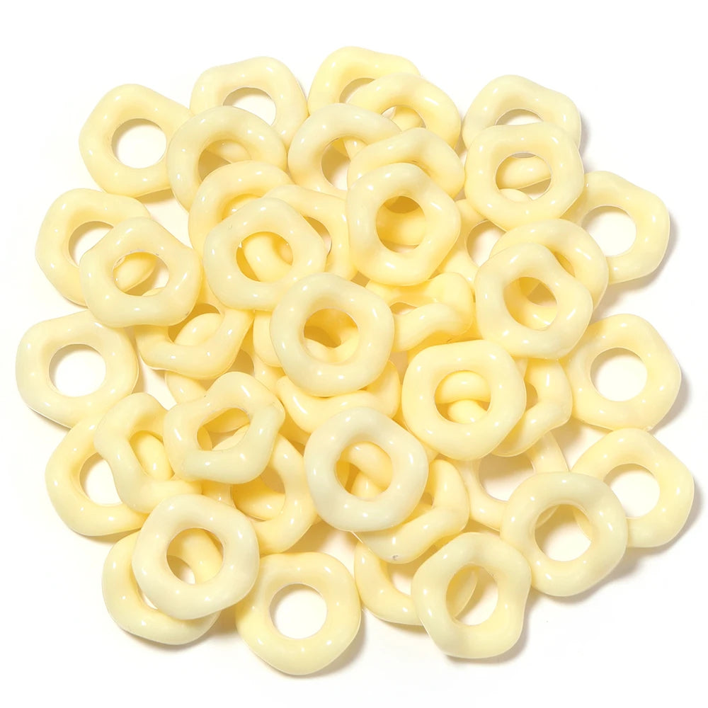 A pile of yellow acrylic spacer beads shaped like small rings for jewelry making