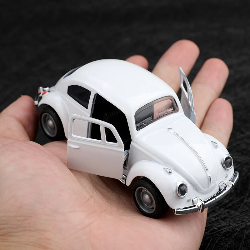 A white 1:38 die-cast model of a classic Beetle car is held in a person's hand.