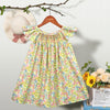 A yellow and pink floral smocked summer dress for girls with flying sleeves displayed on a hanger.