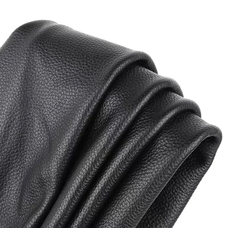 A close-up of premium black cowhide leather with a lychee texture, folded and draped.