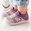 A pair of purple and beige breathable anti-slip baby first walker shoes worn by a child.