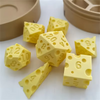 Yellow cheese dice set with various numbered cubes and a carrying case on a white surface