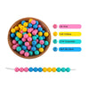 A wooden bowl filled with various silicone round beads in pink, yellow, and blue colors.