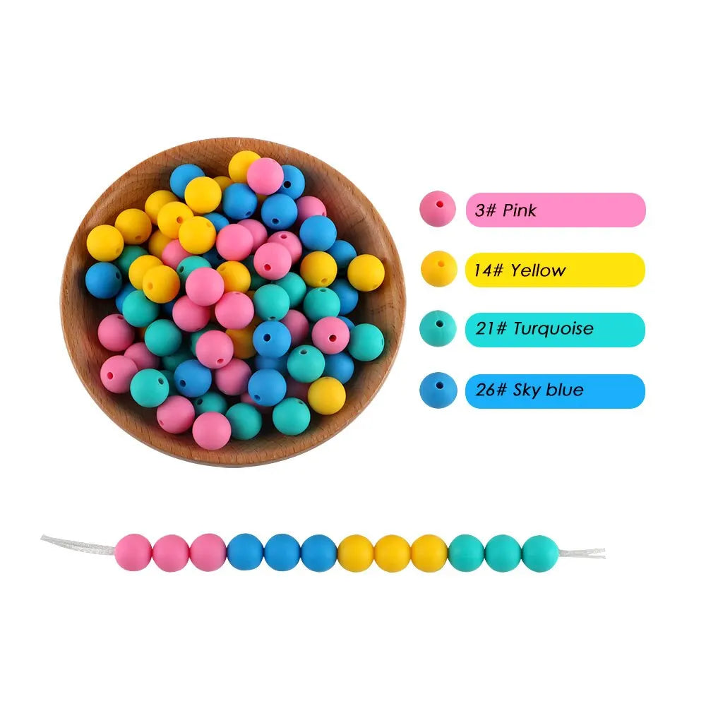A wooden bowl filled with various silicone round beads in pink, yellow, and blue colors.