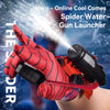 A hand wearing a red spider-patterned glove is launching a stream of water from a black gun launcher.