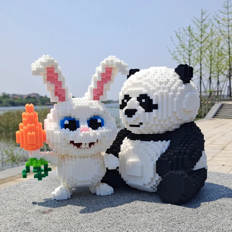 A white building block model of a panda with black markings and pink ears, standing next to an orange flower.