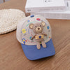 A beige toddler baseball cap featuring a 3D bear design and an adjustable strap, resting on a wooden surface.