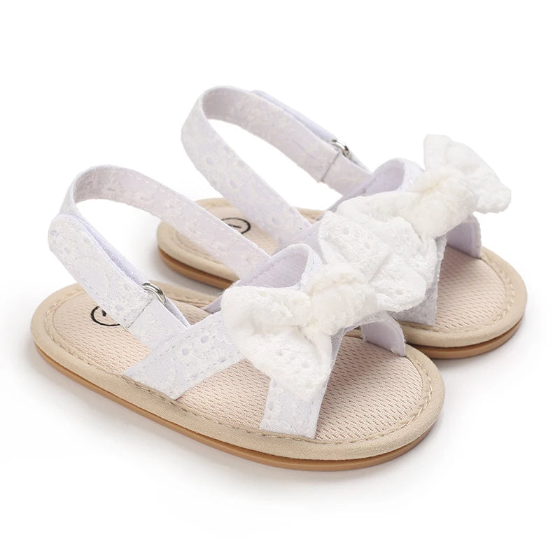 Pair of light purple baby first walker sandals with white fluffy bow details and soft anti-slip soles