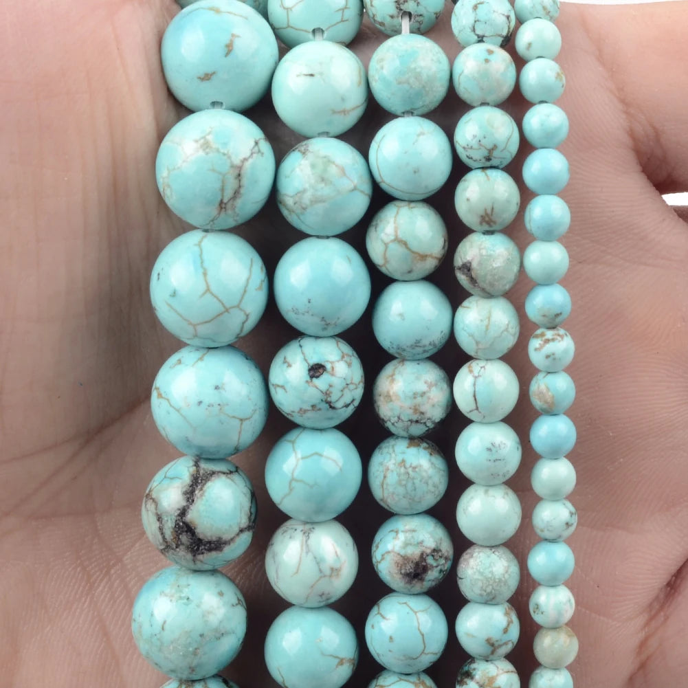 A string of light blue turquoise beads with natural marbling are held in a hand.