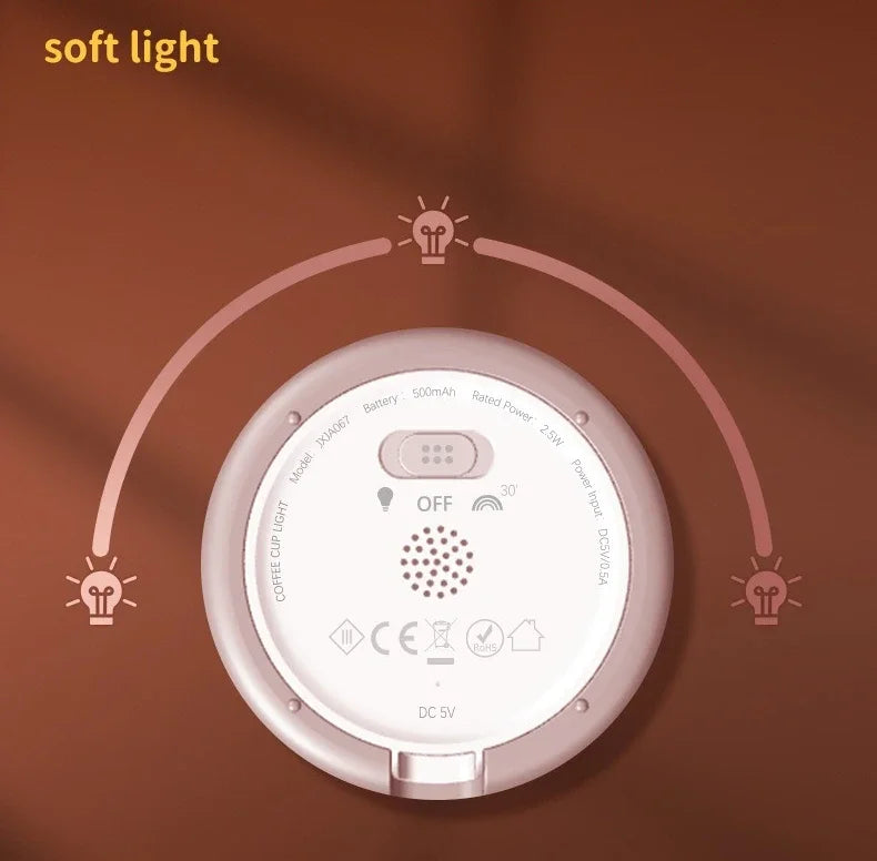 A round, pink night light shaped like a coffee cup, emitting soft light, shown against a brown background.
