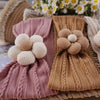 A collection of knitted floral elastic baby headbands in pink and beige tones.