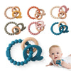 Eine Sammlung von Silikon-Dutzelfäustlingen in verschiedenen Farben und Designs, darunter Bärenformen, für Babys.