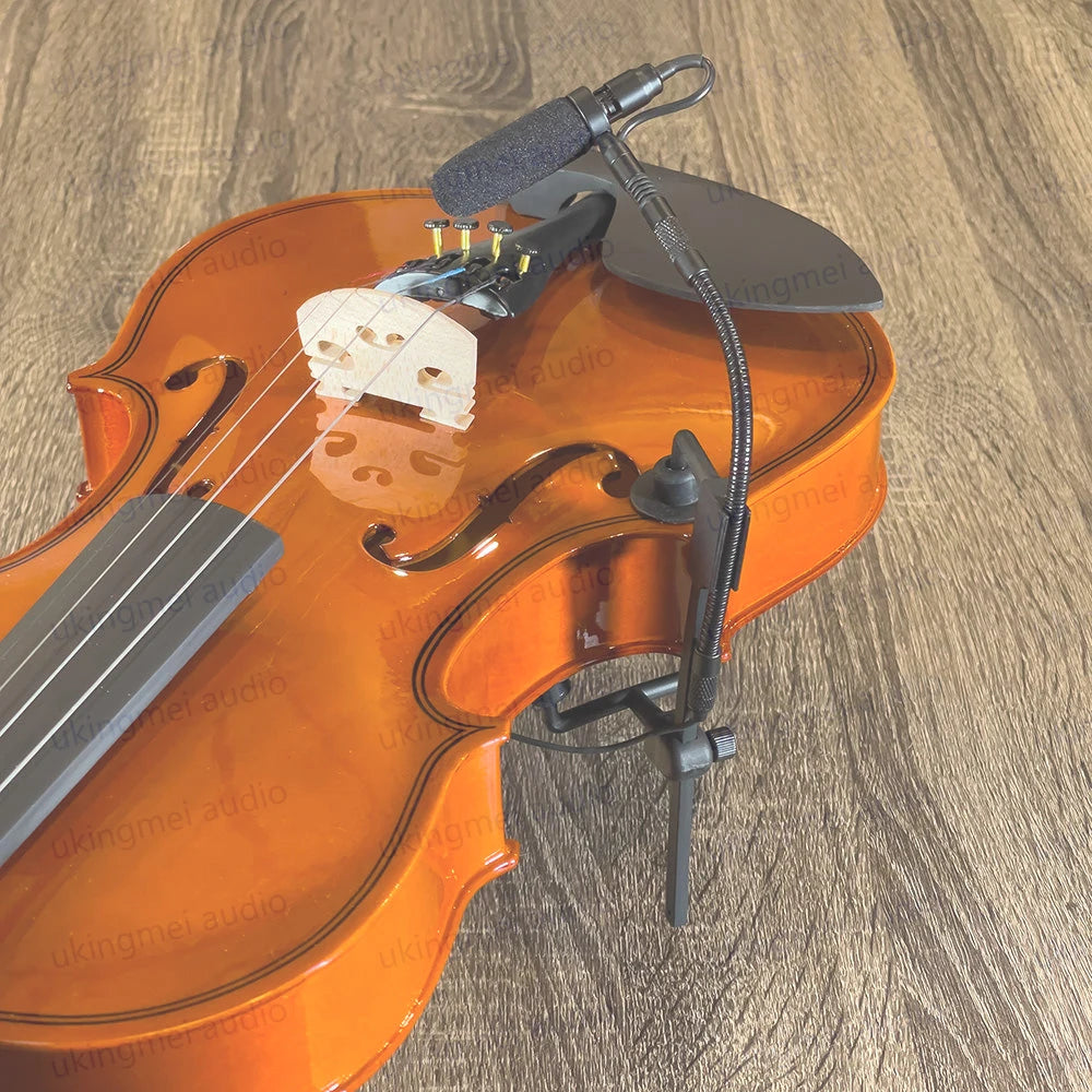 An orange acoustic guitar with a clip-on condenser microphone attached via a gooseneck mount.