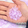 A hand holds a pile of pink sakura flower crystal glass beads for jewelry making