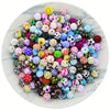 A colorful assortment of 15mm printed silicone beads for DIY jewelry making scattered on a white marble plate.