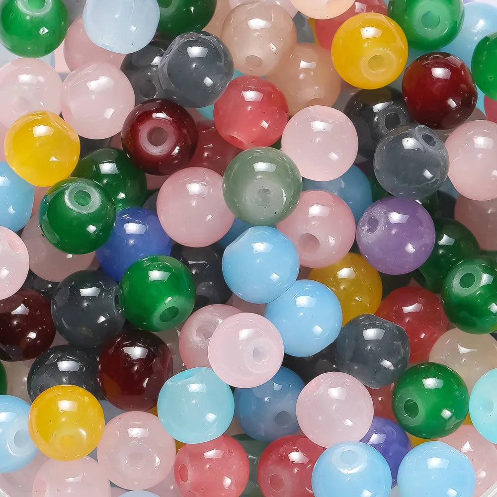 A close-up view of various colorful 6mm glass round beads in shades of green, yellow, pink, purple, and blue.