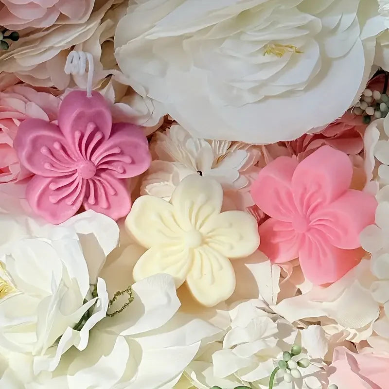 A close-up of various pink and white silicone flower molds for soap, candles, and crafts.